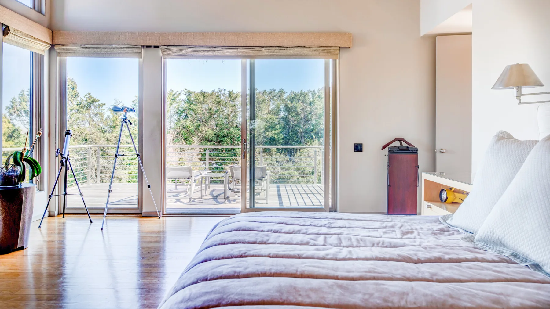 Un dormitorio luminoso con una cama junto a grandes puertas de cristal que dan a un balcón.