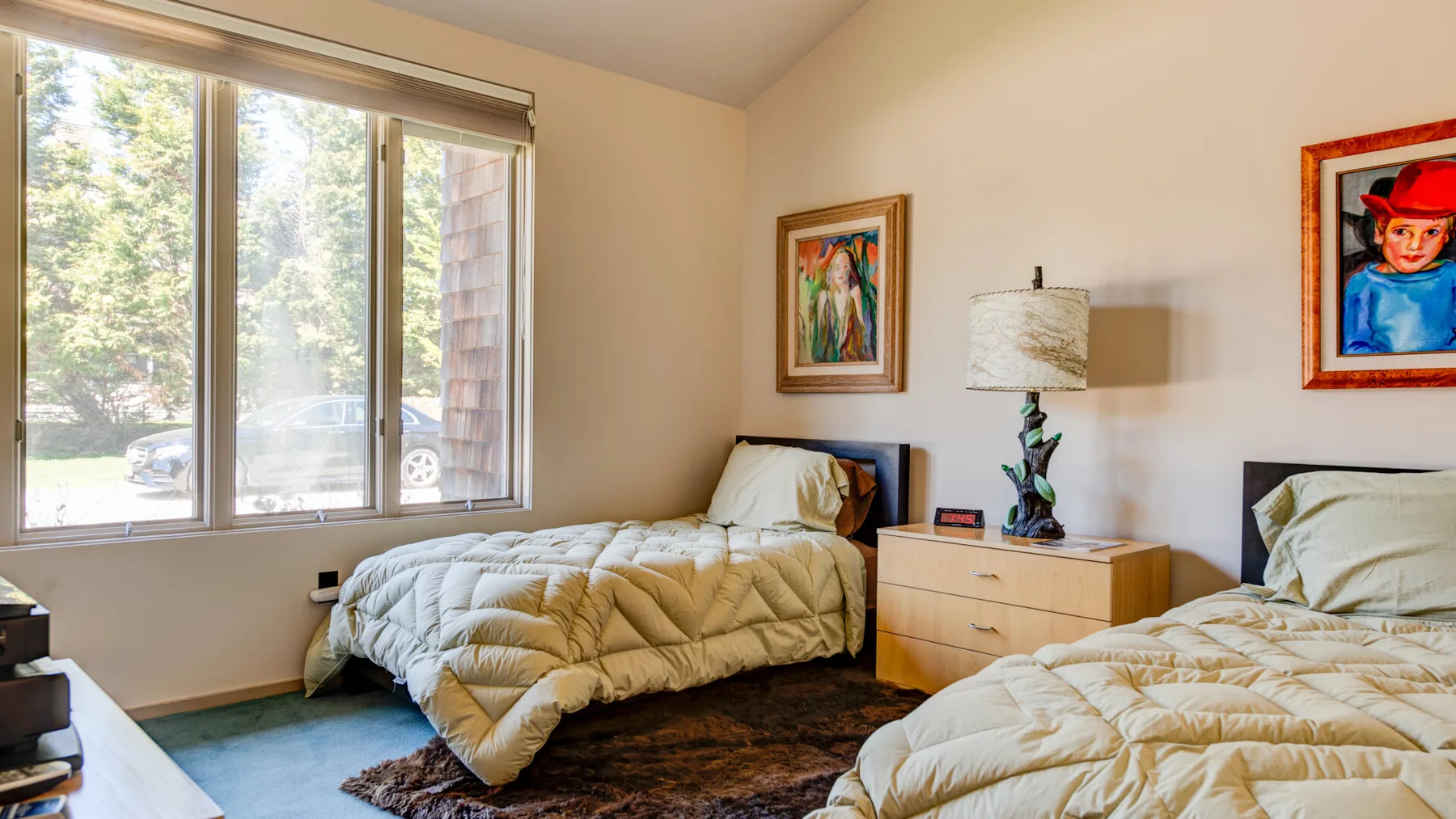 Un dormitorio con dos camas, una ventana y cuadros enmarcados.