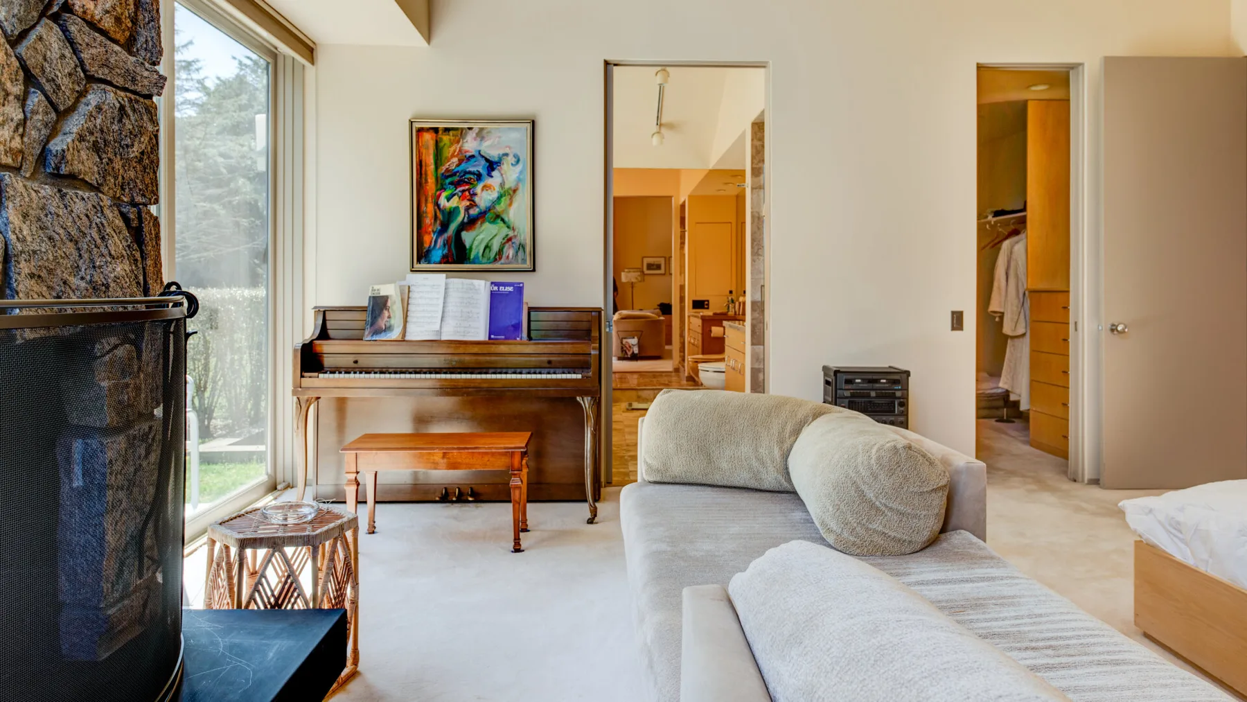 Un dormitorio luminoso con cama, zona de estar y piano vertical.