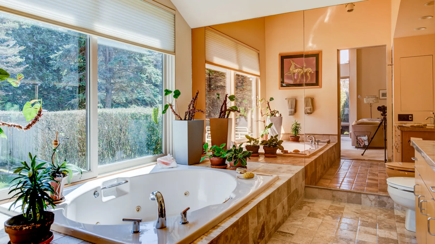Un baño con una bañera grande junto a amplias ventanas y un tocador largo.