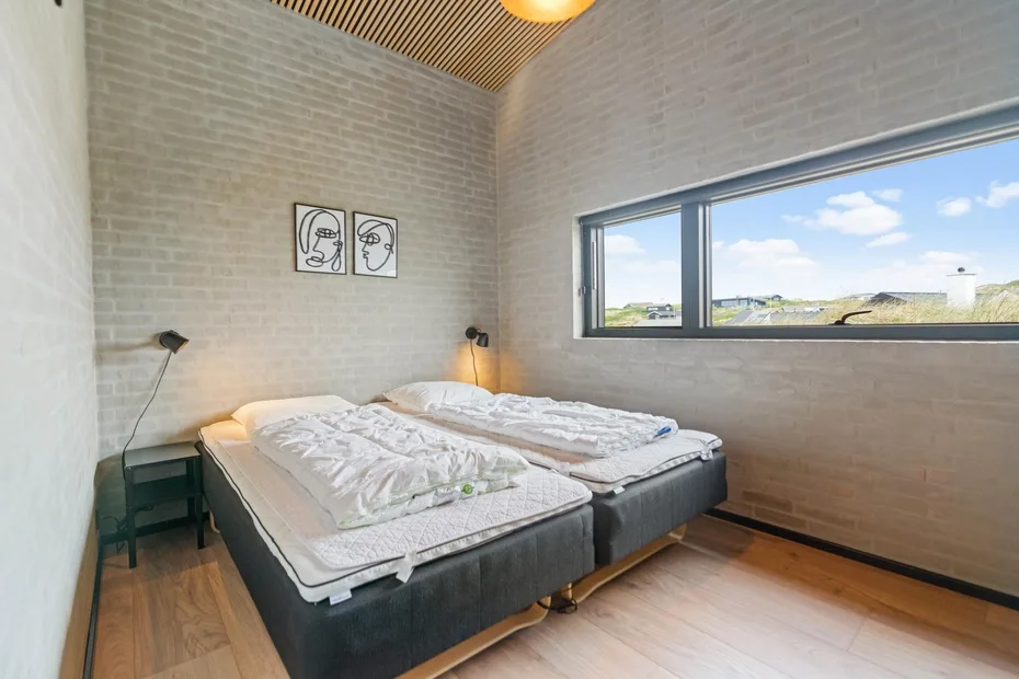 Dormitorio con dos camas, mesitas de noche y una ventana amplia.