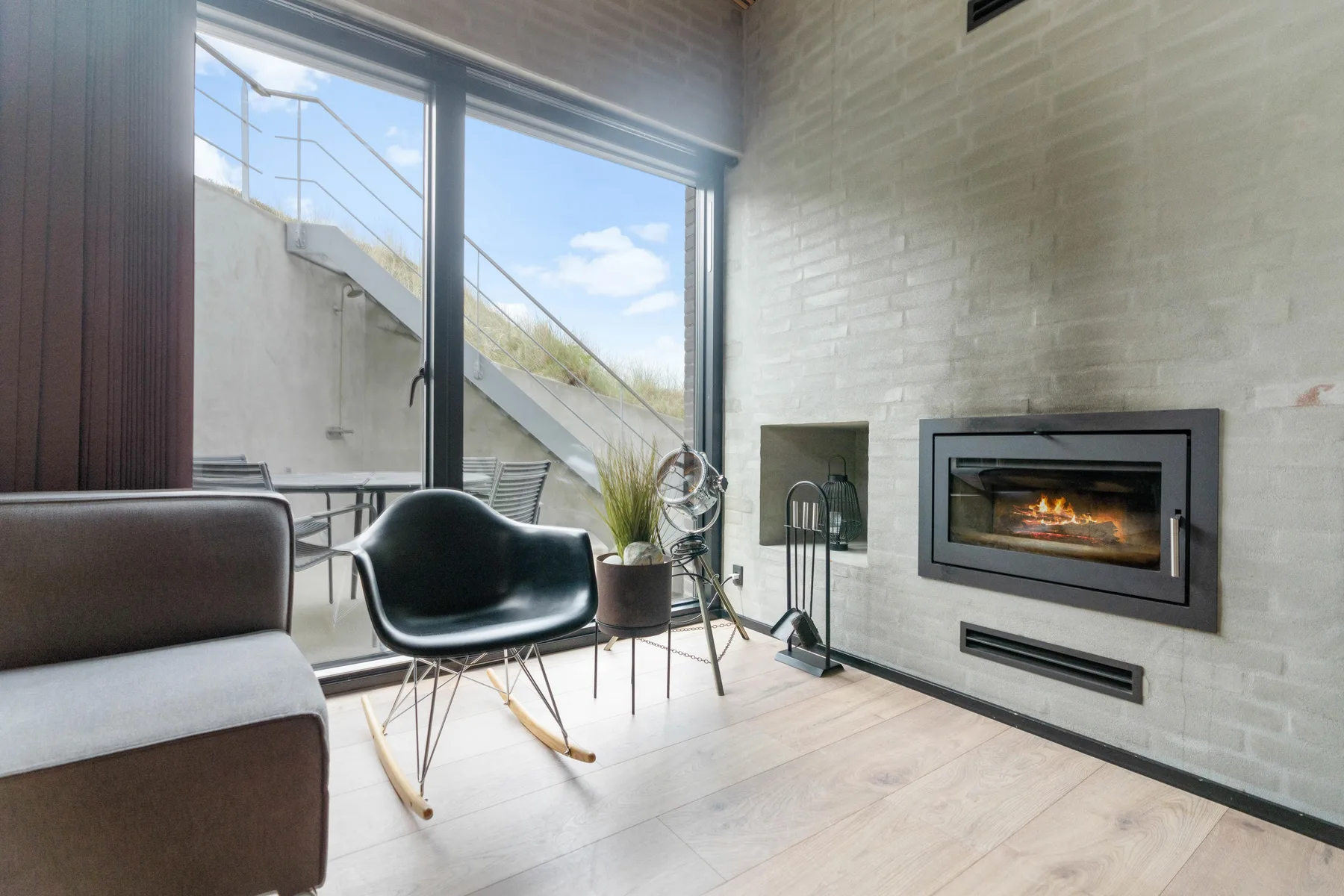 Una sala luminosa tiene una chimenea junto a grandes puertas de vidrio.