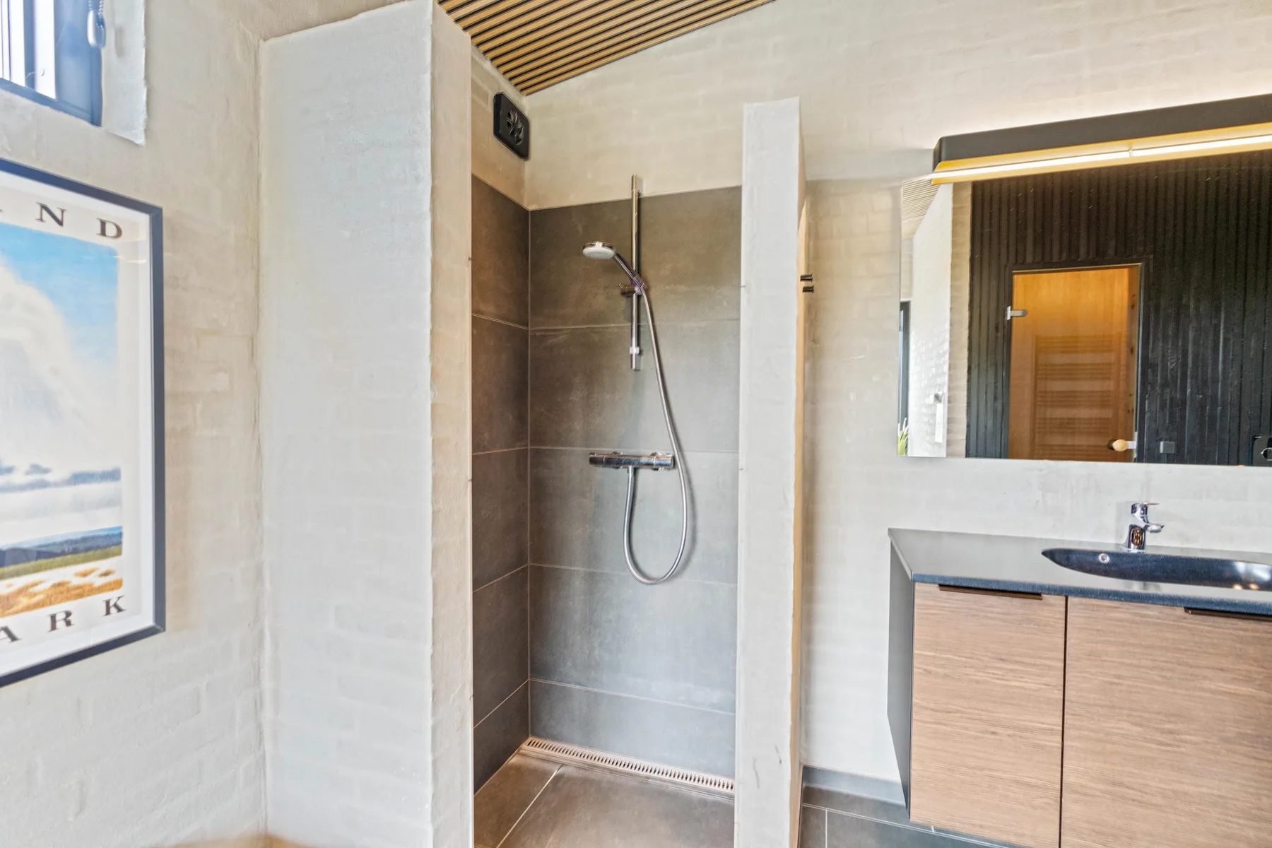 Un baño con ducha revestida de azulejos y un tocador con lavabo.