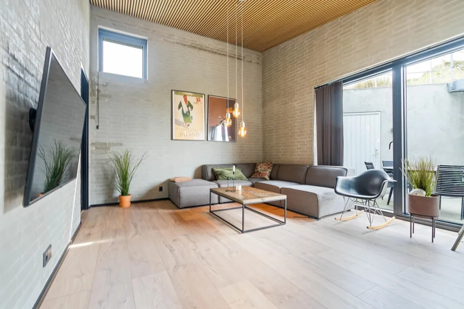 Una sala luminosa con una zona de asientos seccionales y grandes puertas de vidrio.