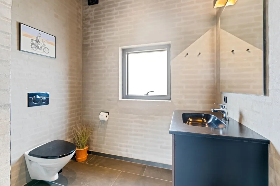 Un baño compacto con inodoro, lavabo y una ventana pequeña.