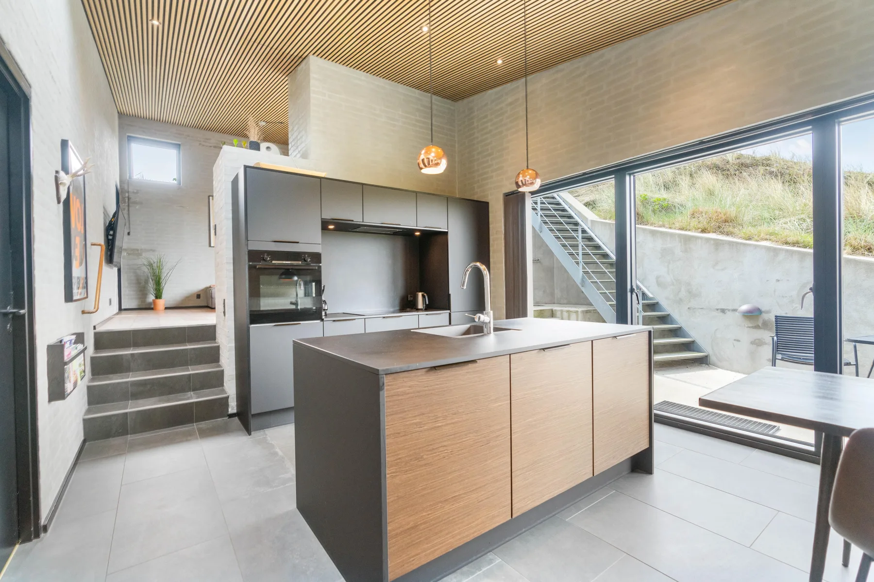 Una cocina moderna con isla y grandes ventanales con vistas a una zona exterior.