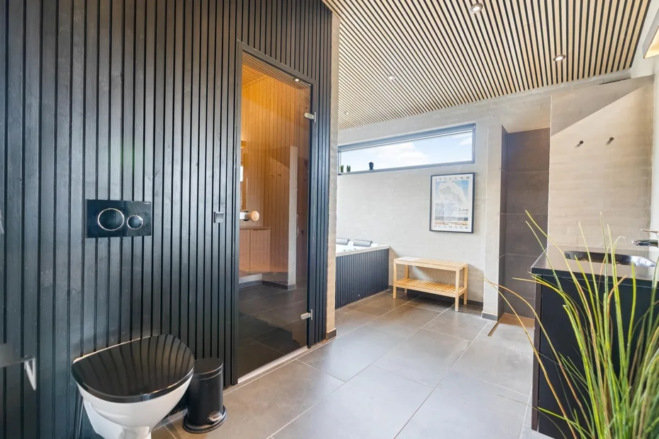 Un baño moderno con ducha, lavabo y un banco de madera.