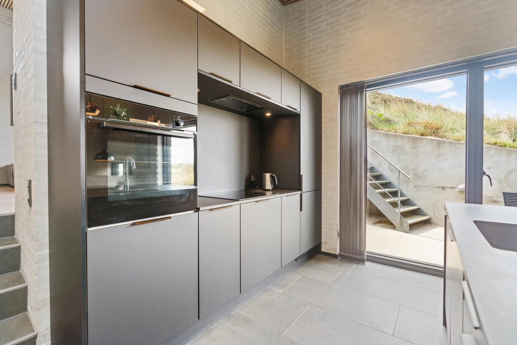 Una cocina moderna con electrodomésticos integrados y una amplia puerta de vidrio al patio.