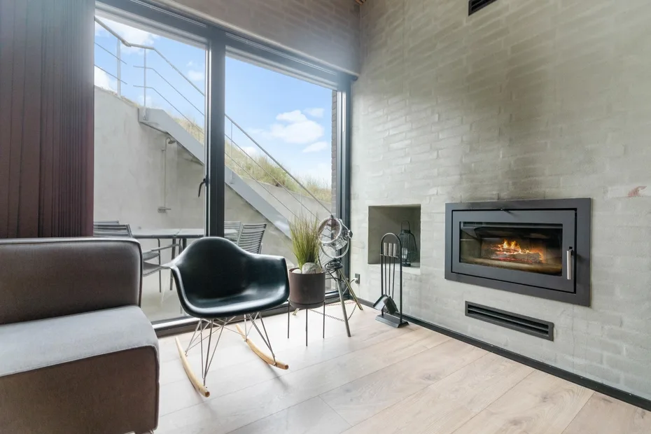 Una sala de estar moderna con chimenea y grandes ventanales.
