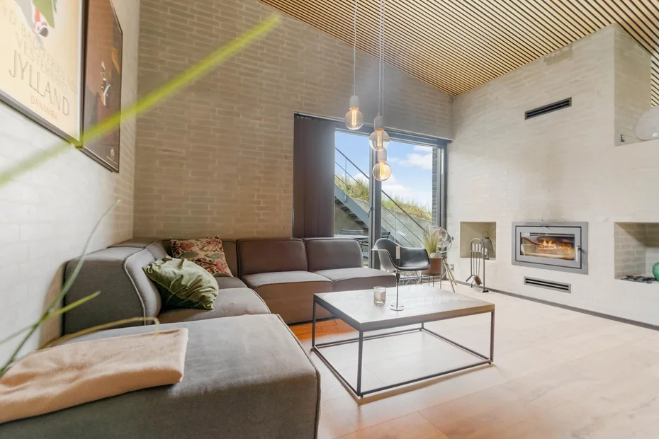 Una sala de estar moderna con asientos seccionales, una mesa de centro y una chimenea.