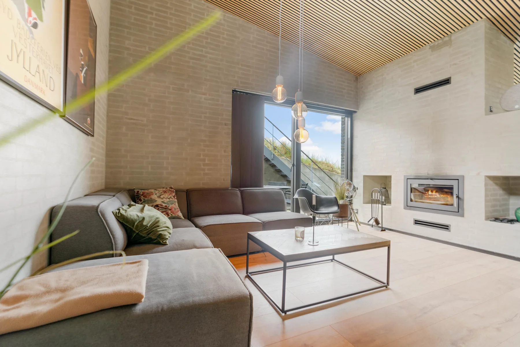 Una sala de estar con asientos seccionales, una mesa de centro de vidrio y una chimenea empotrada.