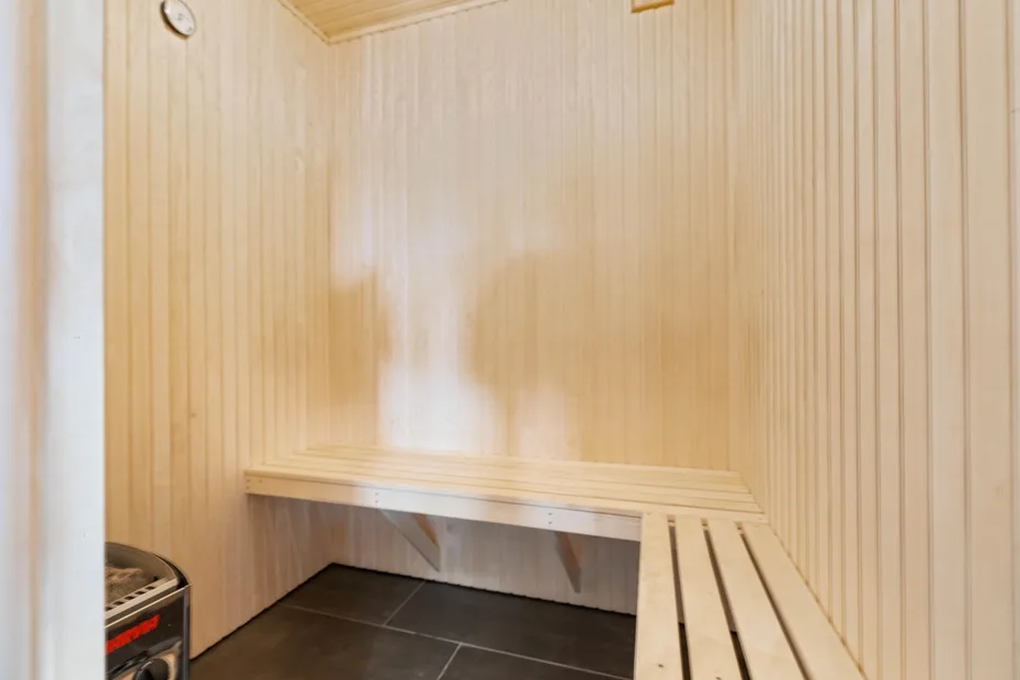 Una sauna revestida de madera con un banco largo y suelo de baldosas oscuras.