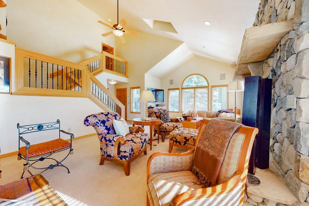 Living room with seating, a staircase, and a stone fireplace.