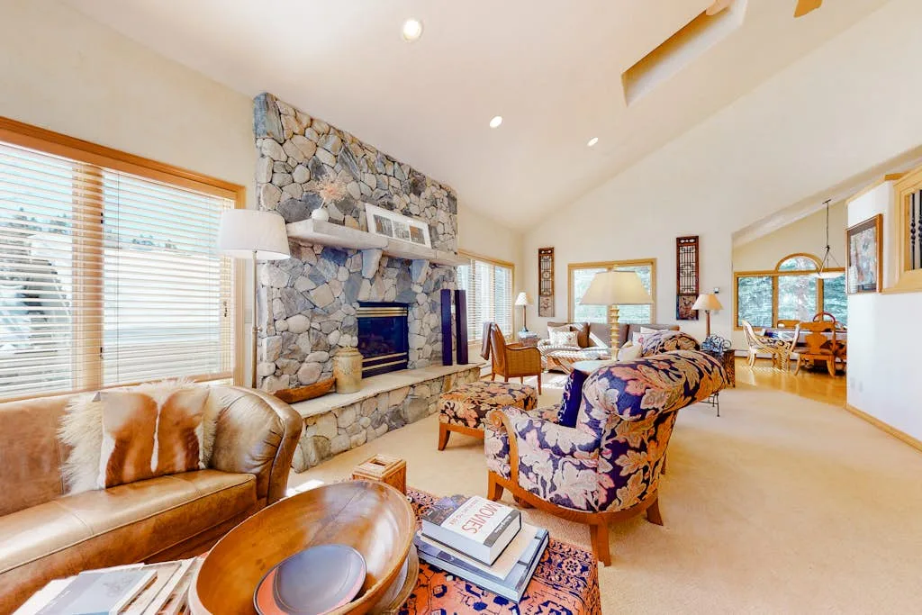 A spacious living room with a stone fireplace and seating.
