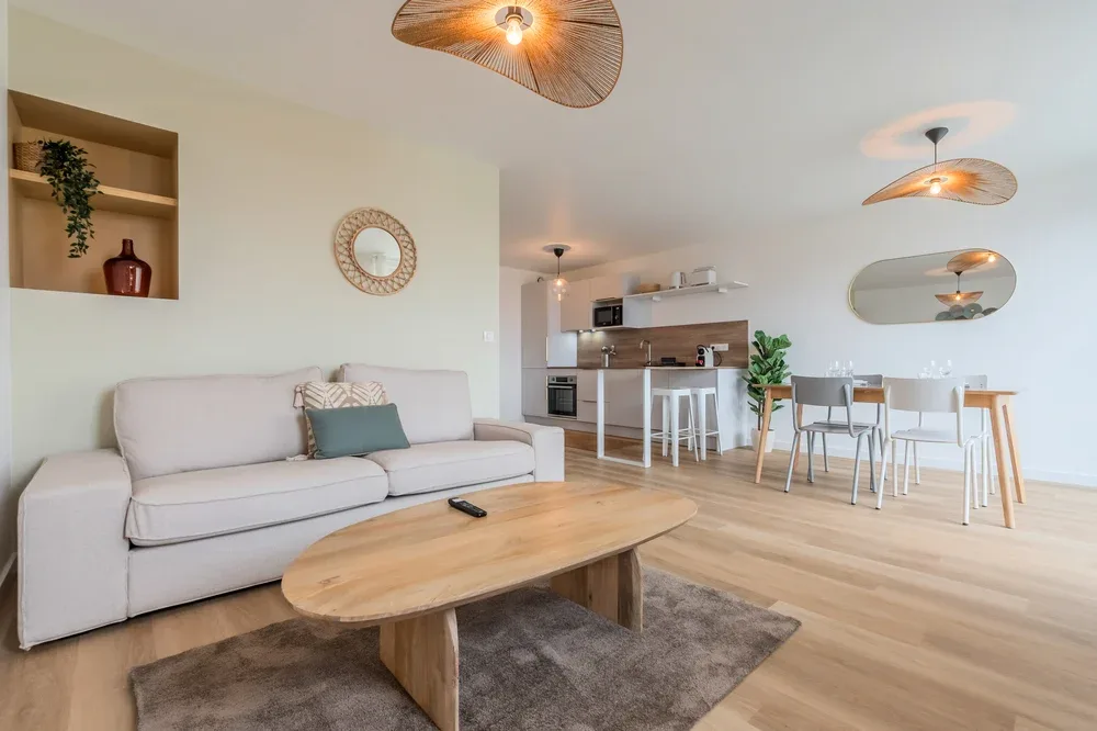 A bright open-plan living and dining area with a sofa and wooden coffee table.