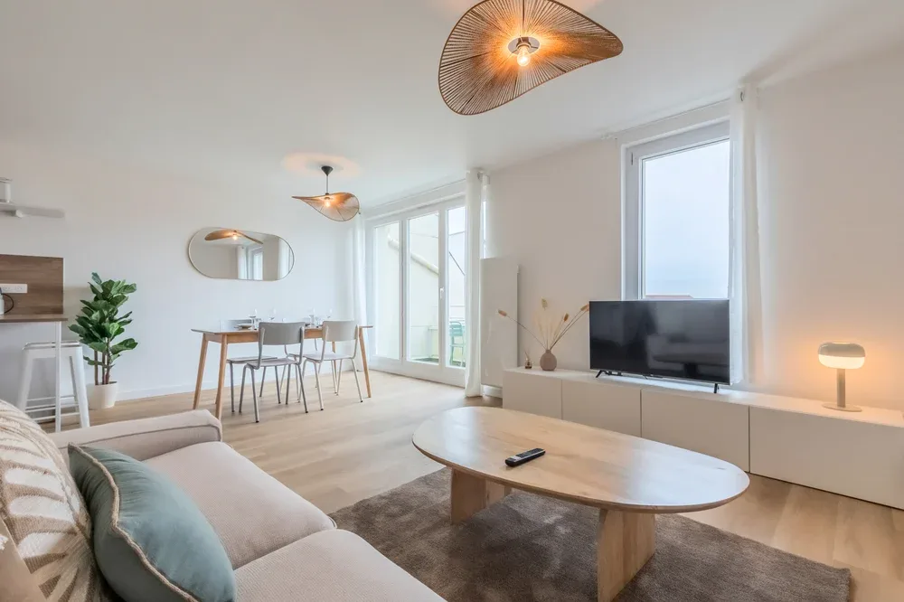Bright living and dining area with a sofa, dining table, and television.