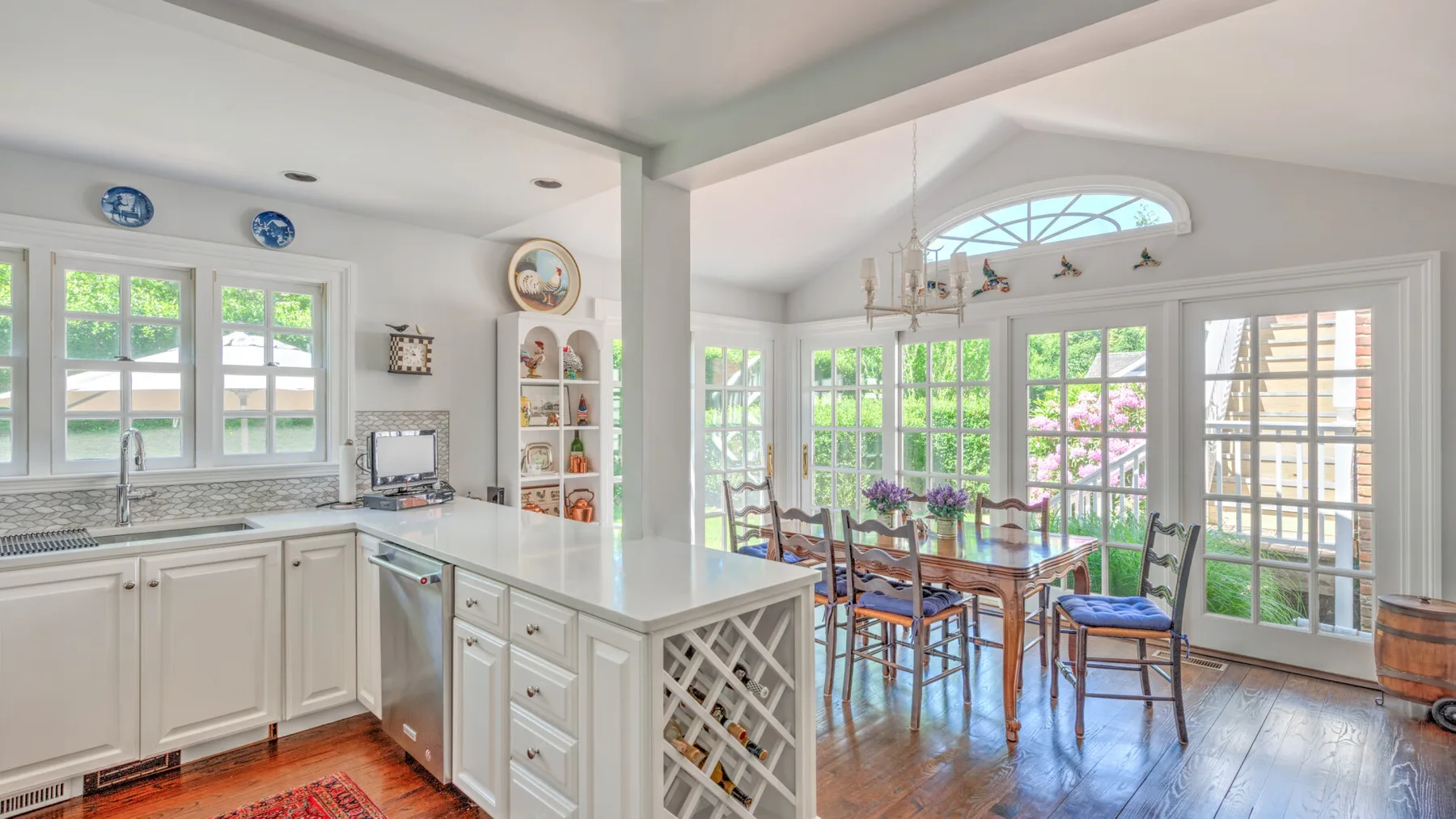 A bright kitchen opens into a dining area with a glass table and large windows.