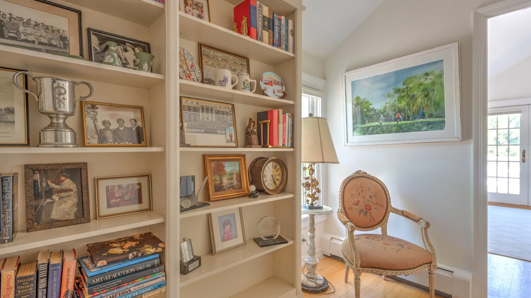 A bright sitting area with a cushioned chair beside built-in bookshelves.