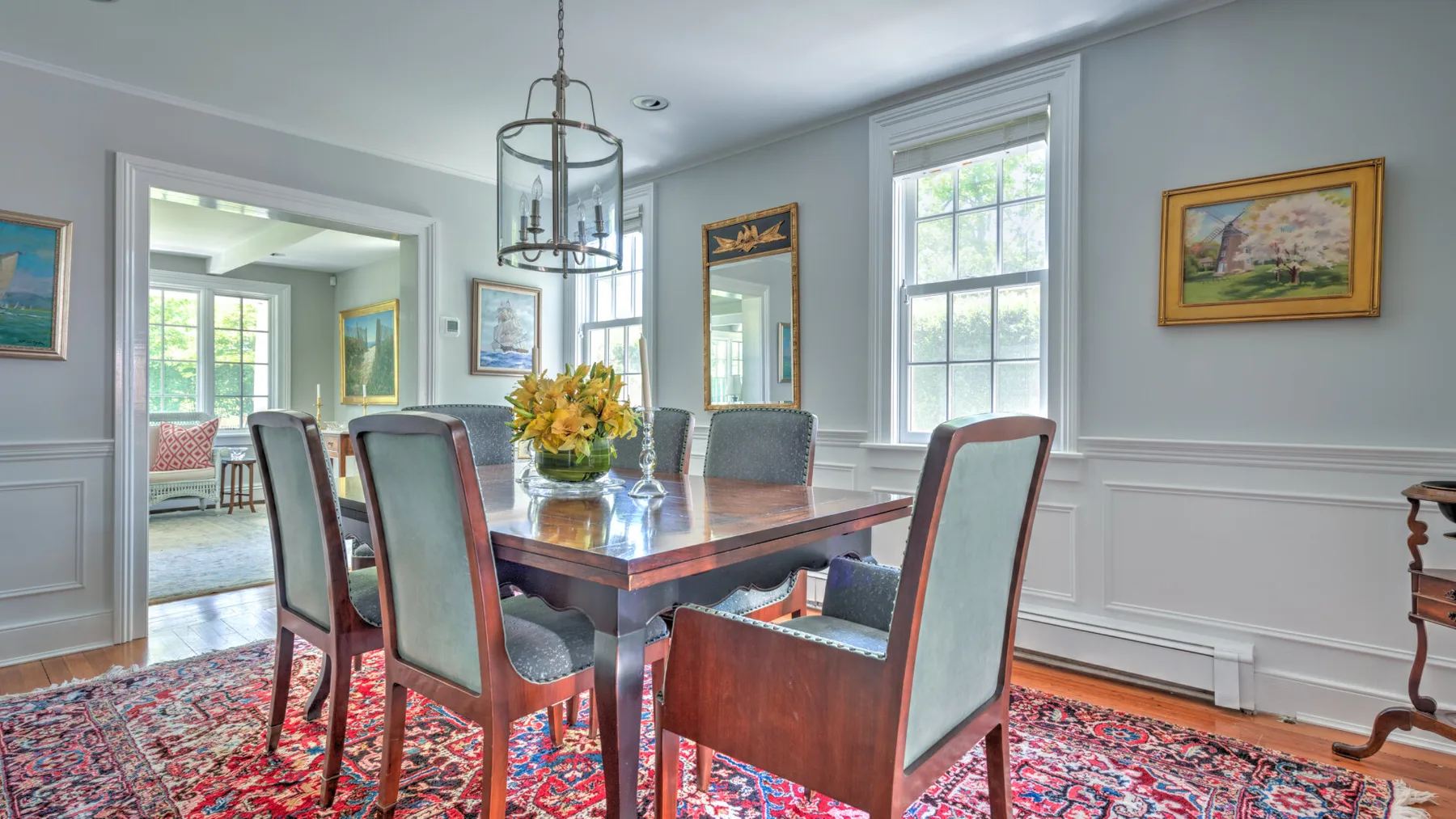 A formal dining room with a wooden table, upholstered seating, and tall windows.
