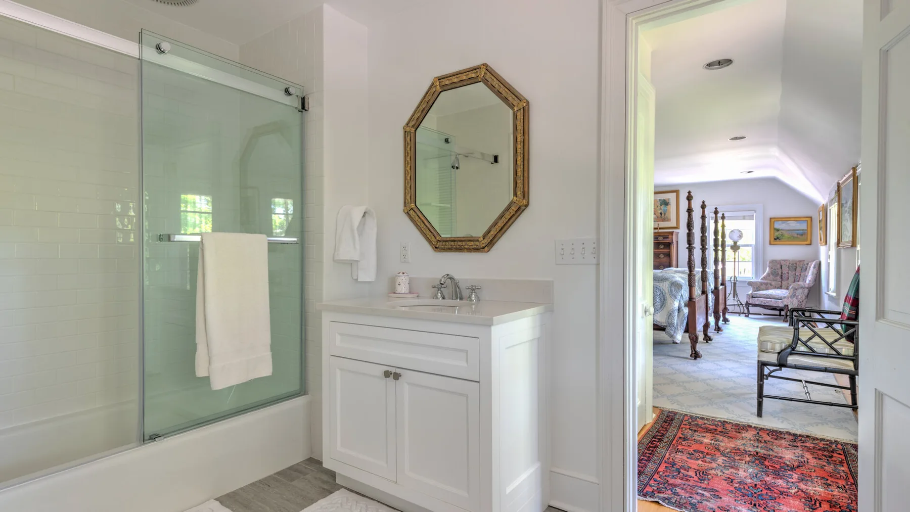A bathroom vanity and glass shower open onto an adjoining sitting area.