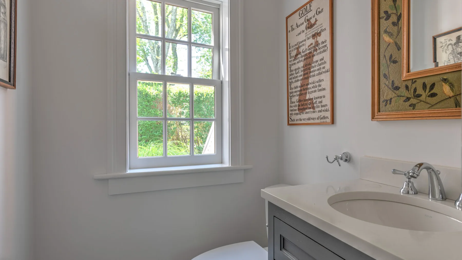 A bright bathroom with a sink beneath framed wall art.