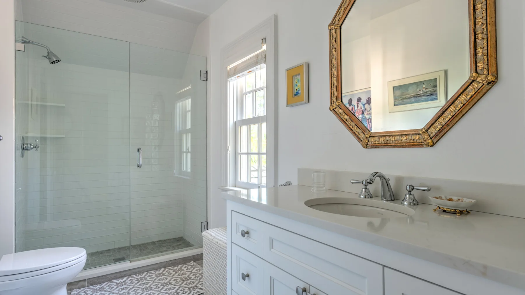 A bright bathroom with a glass shower and a white vanity.