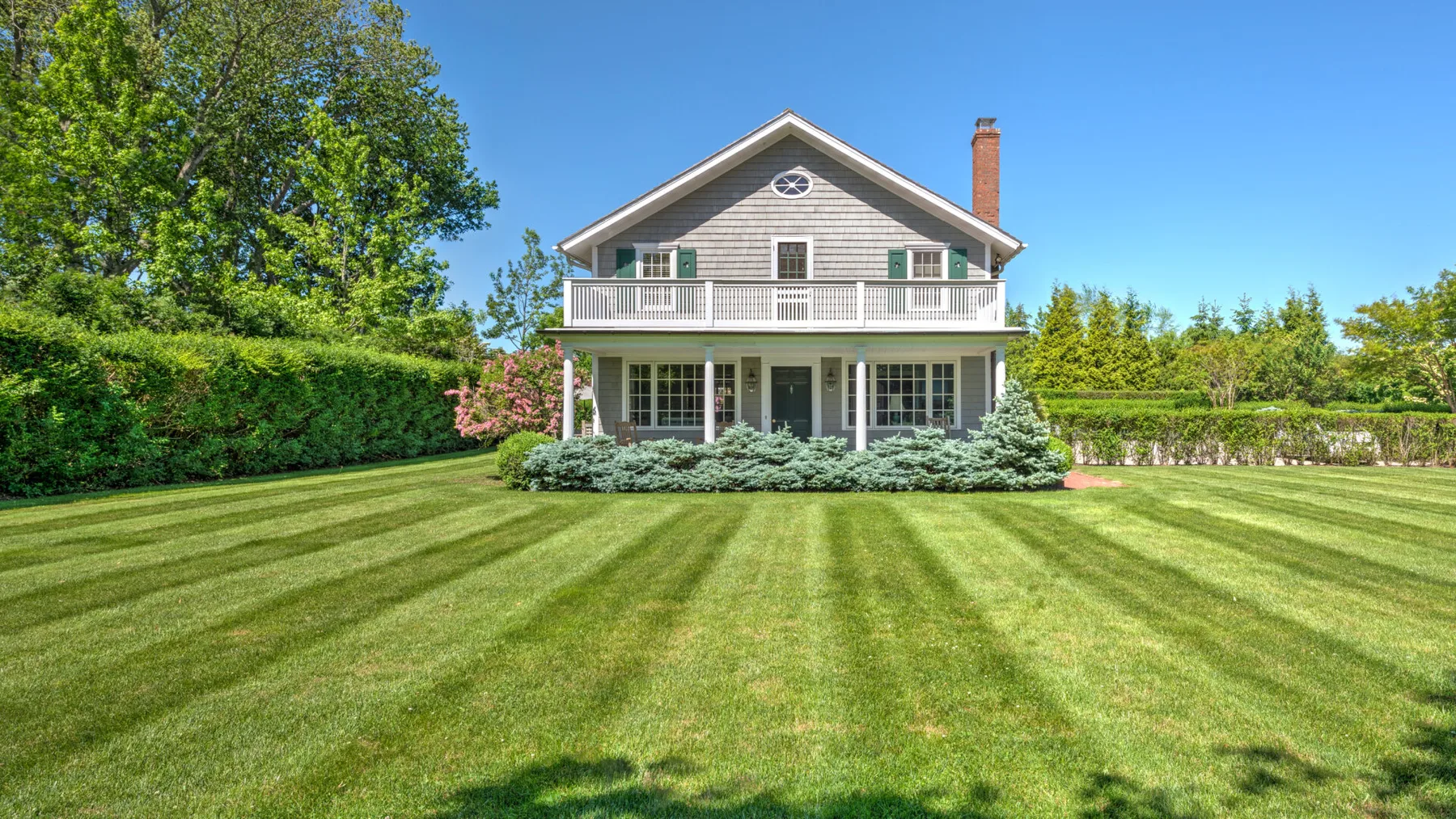 A two-story house stands beyond a broad, freshly mowed lawn.