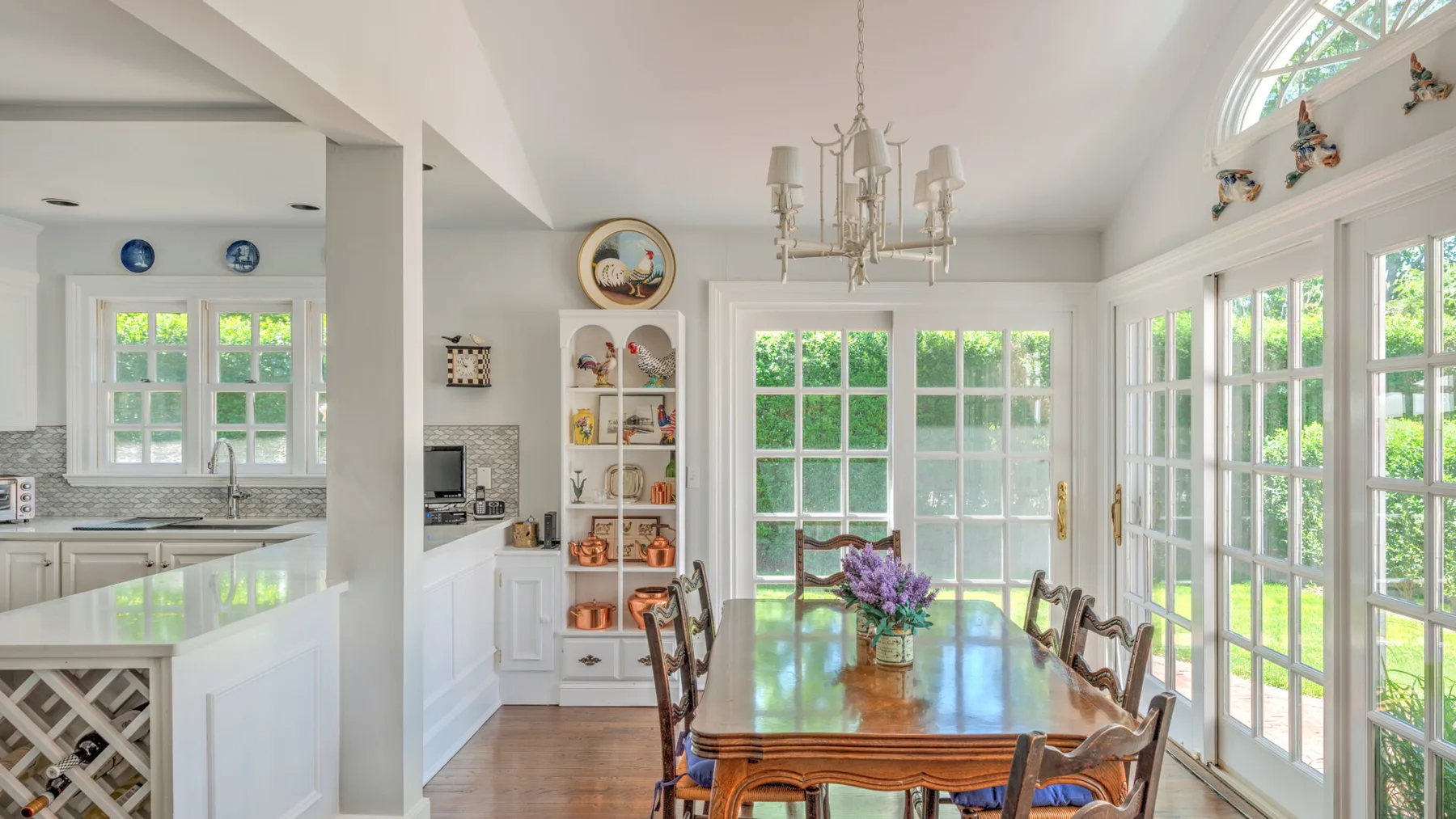 A bright kitchen and dining area with large windows and a wooden dining table.