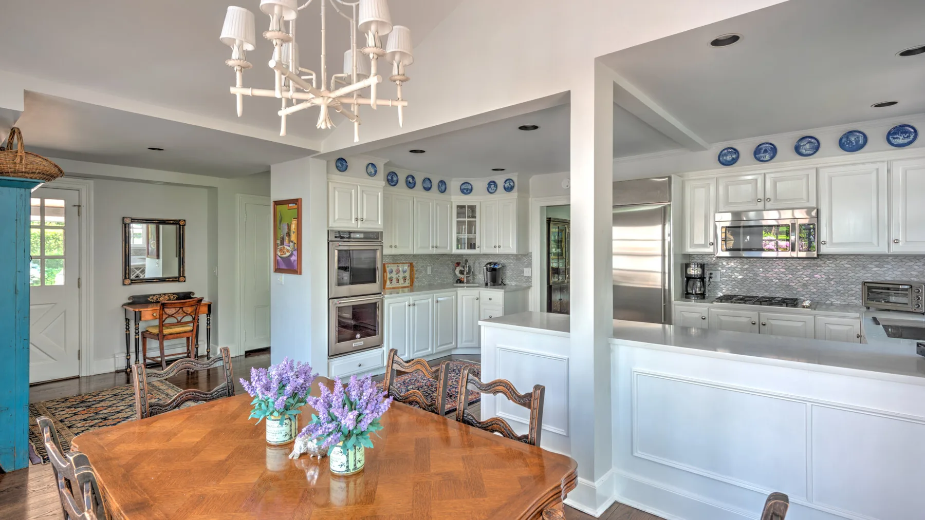 A dining area opens into a bright kitchen, with a wooden table set with flowers.