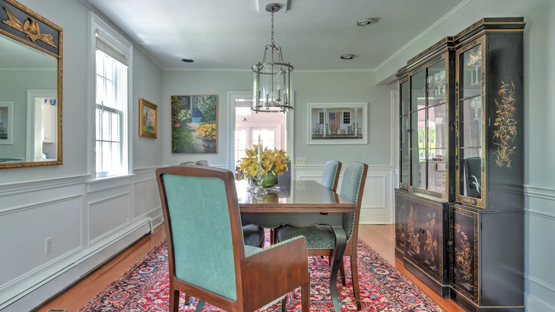 A formal dining room with a dining table, upholstered seating, and a large display cabinet.