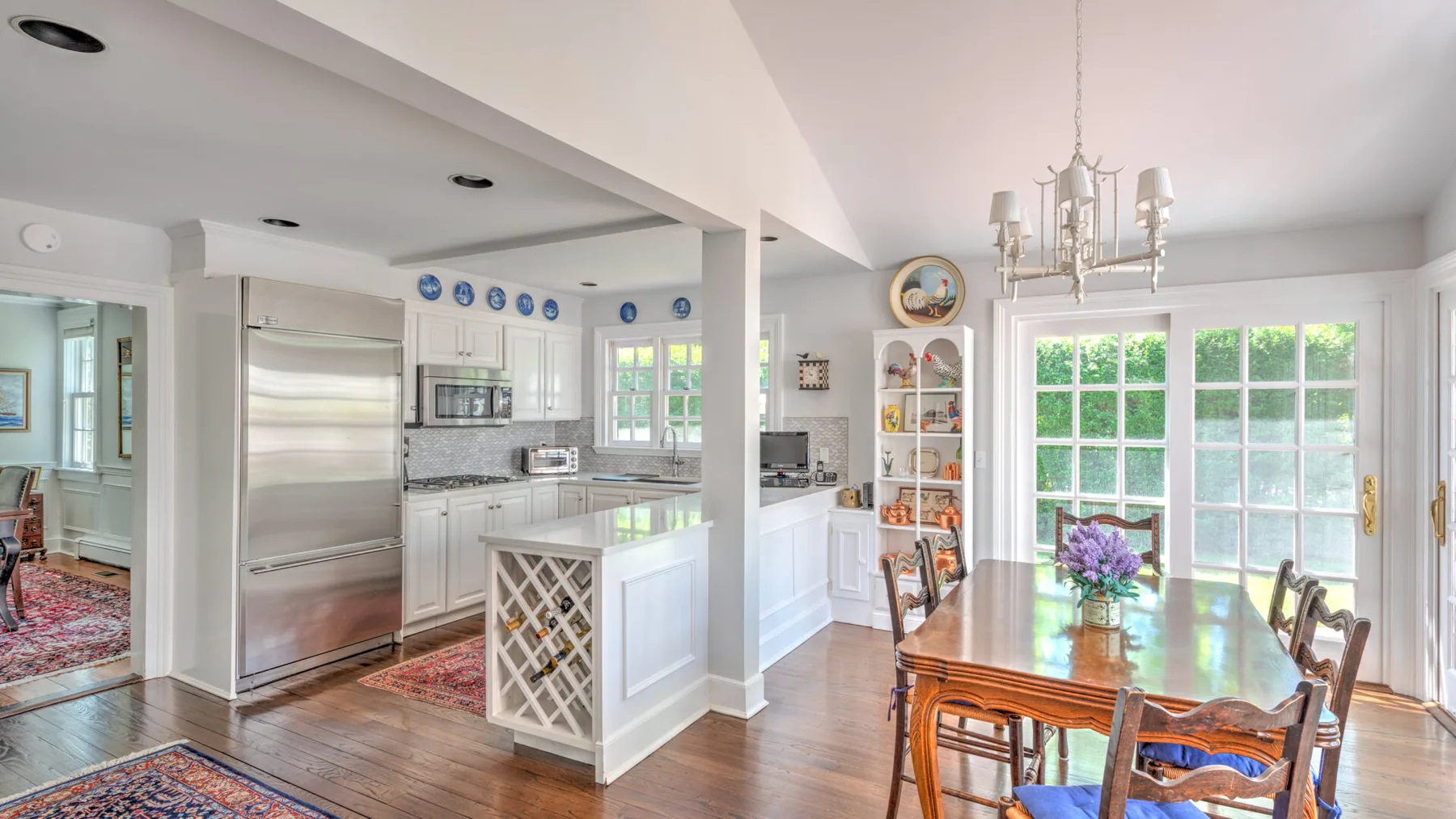 A bright open kitchen and dining area with white cabinetry and a wooden table.