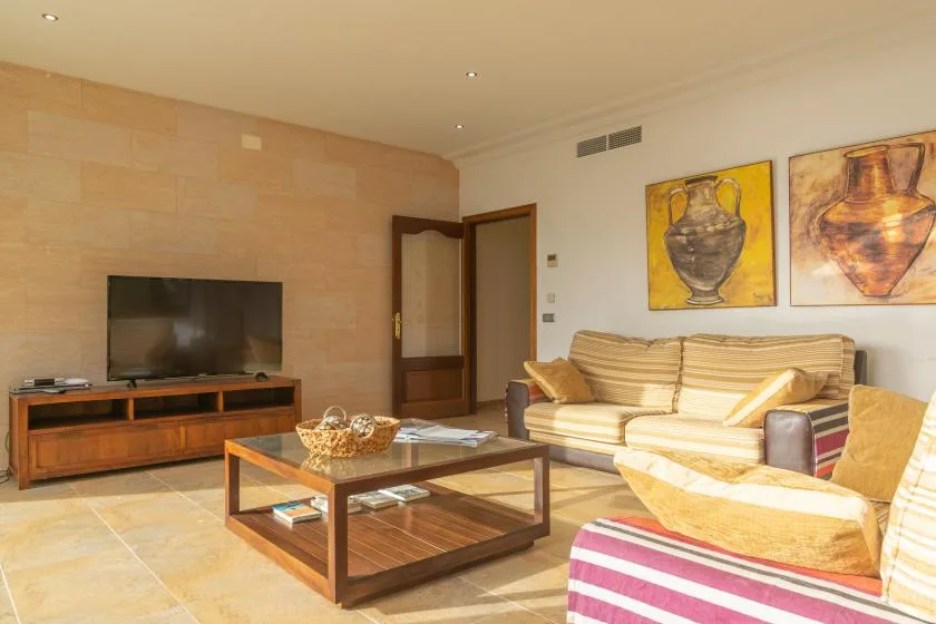 A living room with seating, a television, and framed artwork on the walls.