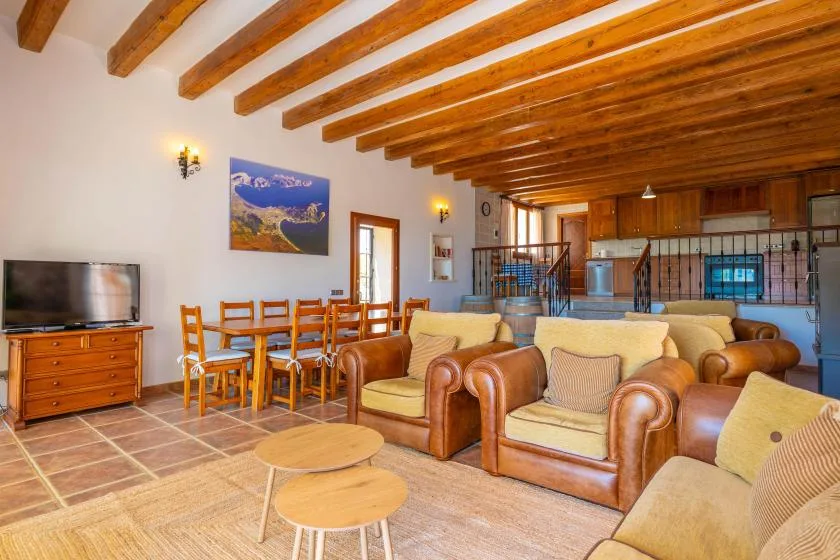 A living room with seating, a dining table, and exposed wooden ceiling beams.