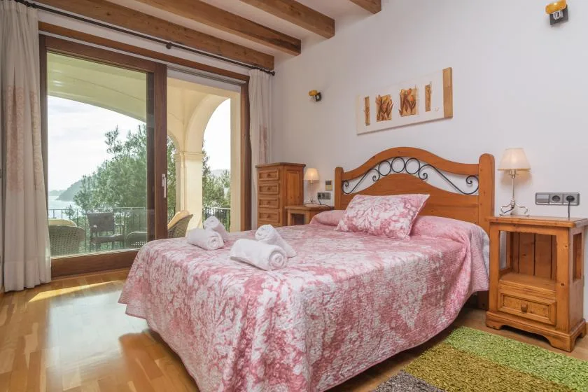 A bedroom with a pink bedspread and sliding glass doors opening onto a balcony.