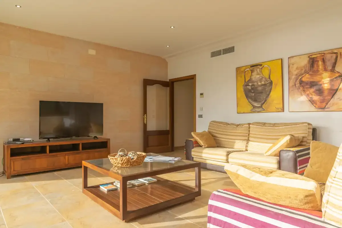 A living room with seating, a television, and colorful artwork on the wall.