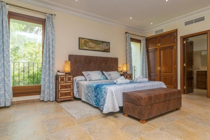 A bedroom with a bed, bedside tables, and a bench at the foot.