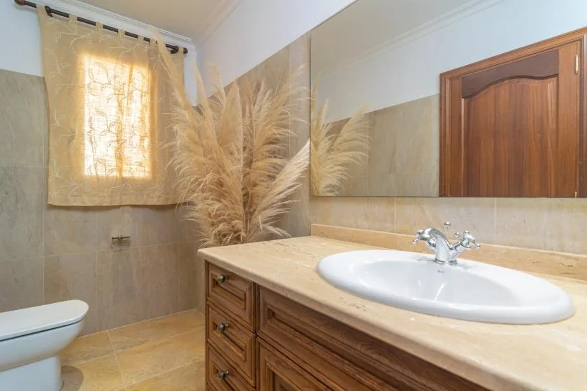 A bathroom with a sink vanity, mirror, and window.