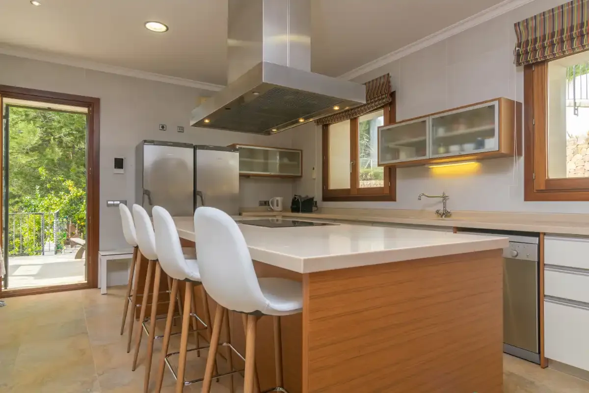 A bright kitchen with a central island and several seats.