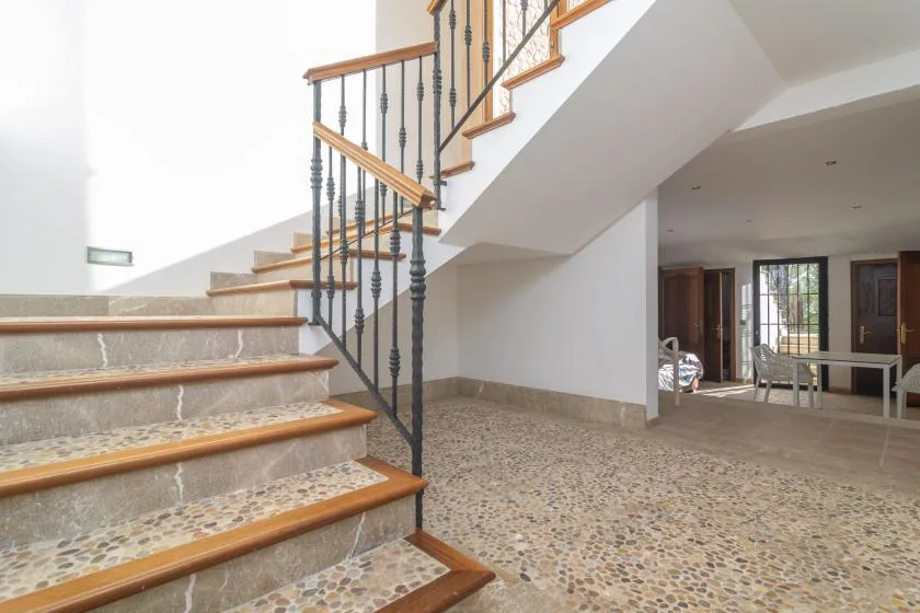 An interior staircase rises above a spacious tiled room.