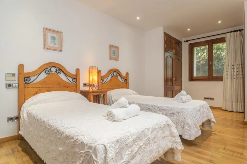 A bedroom with two beds, white bedding, and a window.
