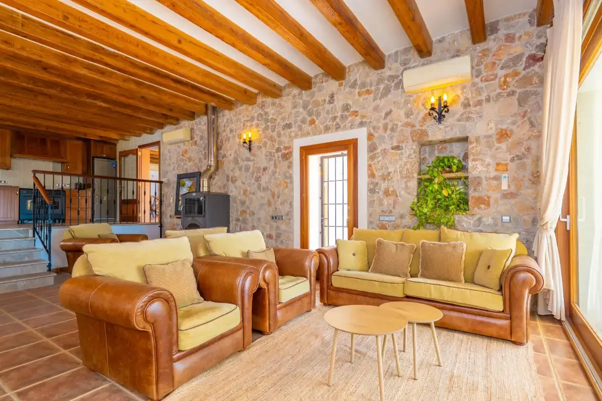 A stone-walled living room has seating around a pair of low tables.