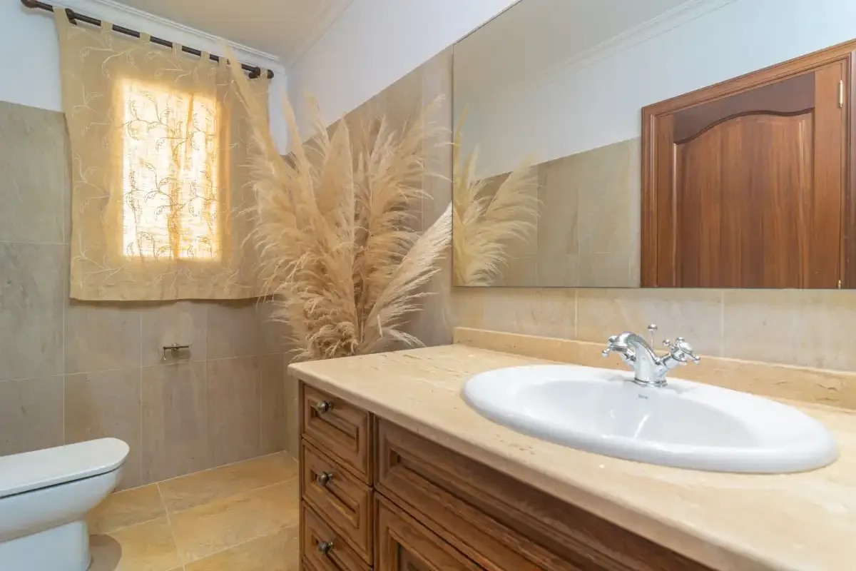 A bathroom with a sink, wooden vanity, and large wall mirror.