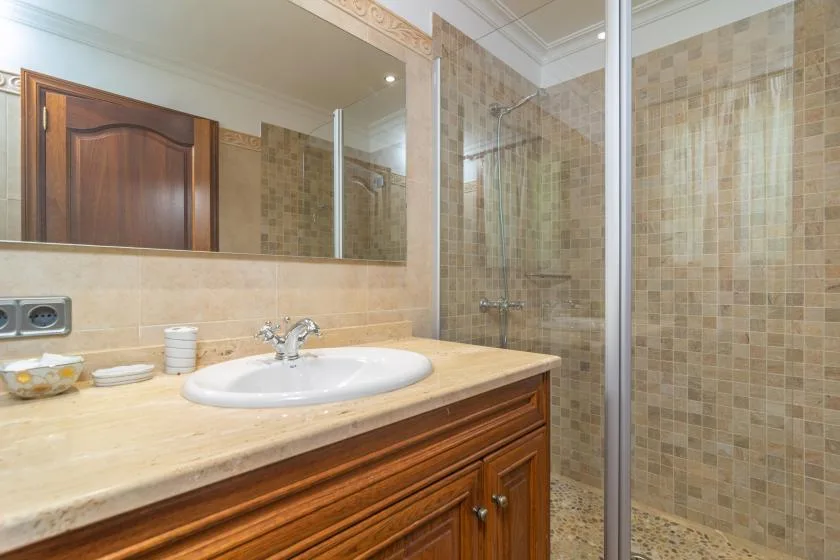 A tiled bathroom with a sink, mirror, and glass shower.
