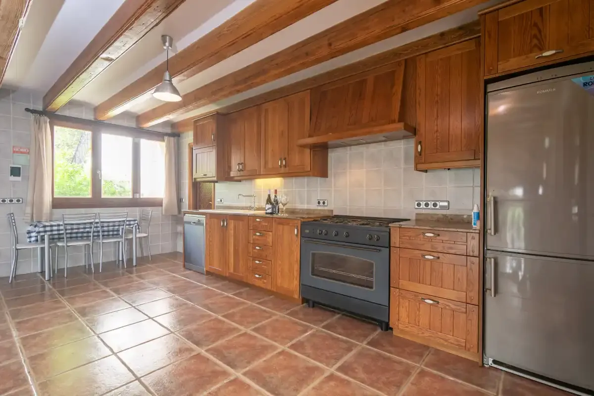 A kitchen with wooden cabinets, a stove, and a dining table by the window.