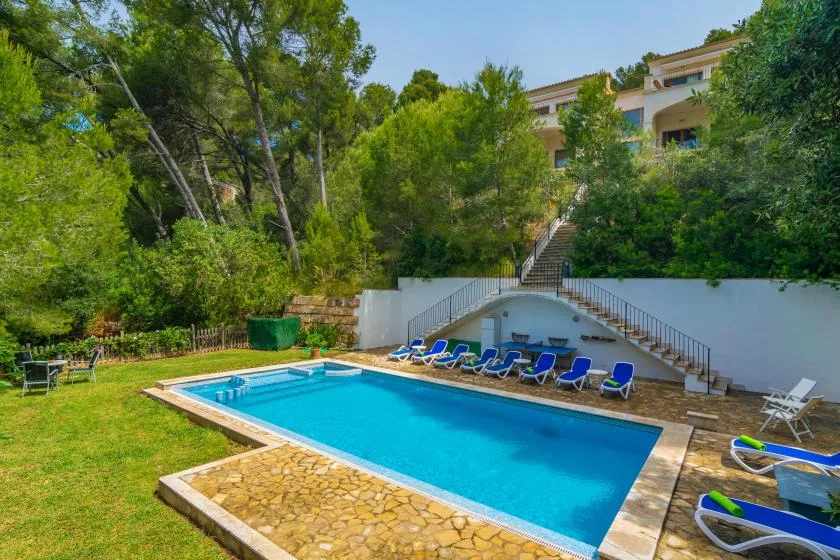 An outdoor swimming pool surrounded by greenery and lounge seating.