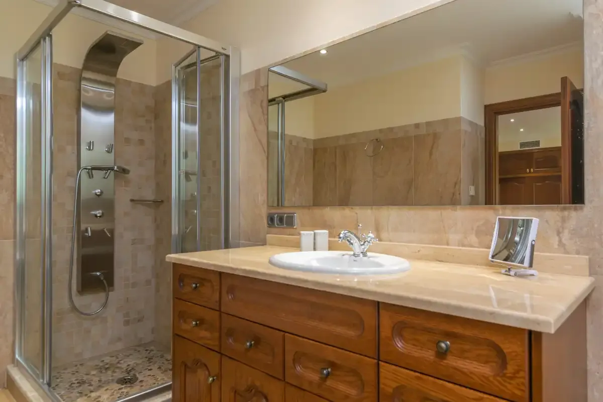 A bathroom with a wood vanity, sink, and glass shower.
