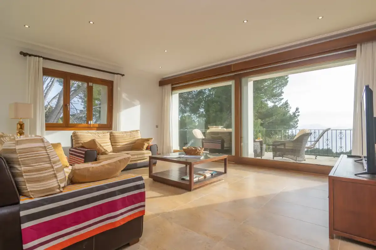 A bright living room with seating and large windows overlooking a terrace.