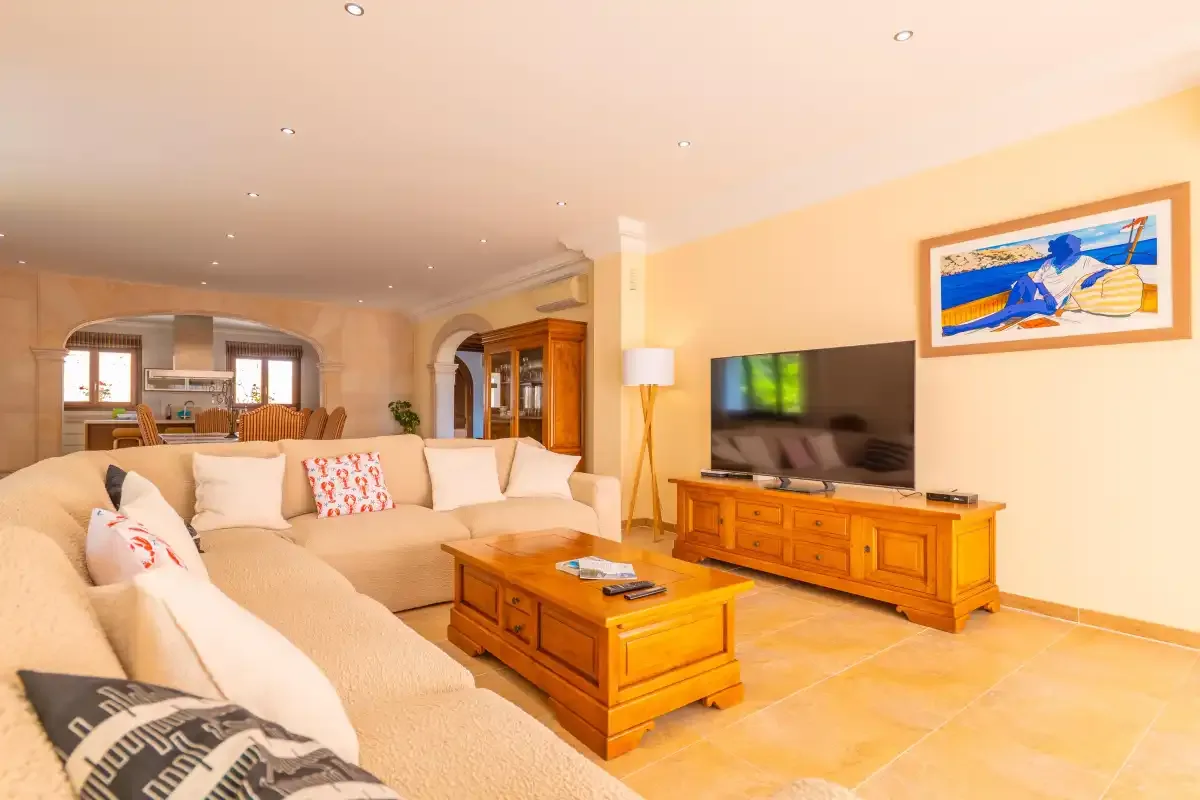 A living room with seating, a television, and wooden tables.