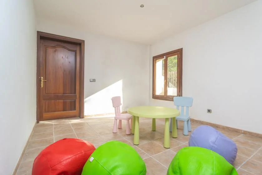 A bright playroom with a small table and colorful children's seating.
