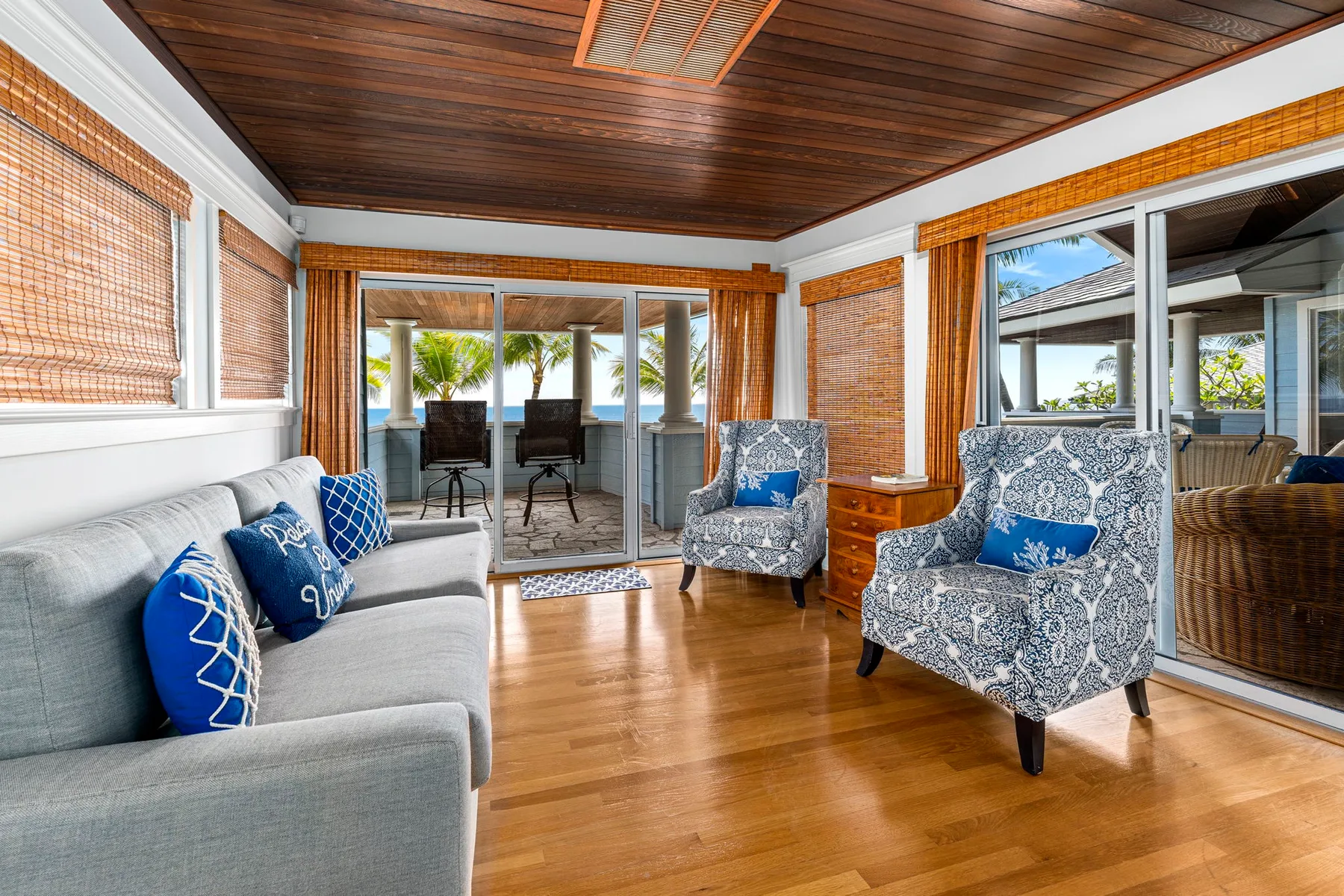 Una sala de estar luminosa con asientos, ventanas grandes y techo de madera.